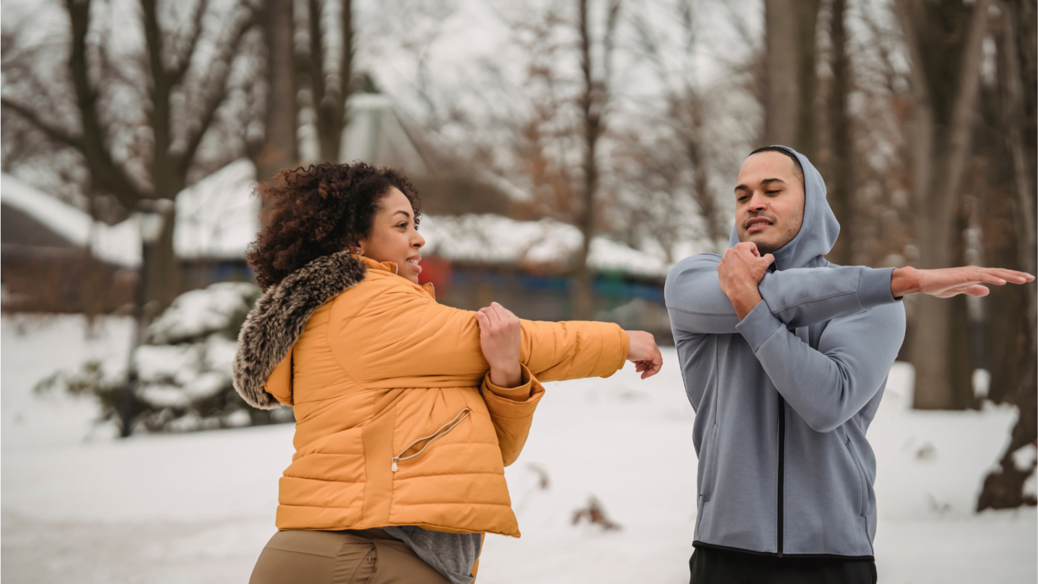 Two people stretching outside with snow on the ground